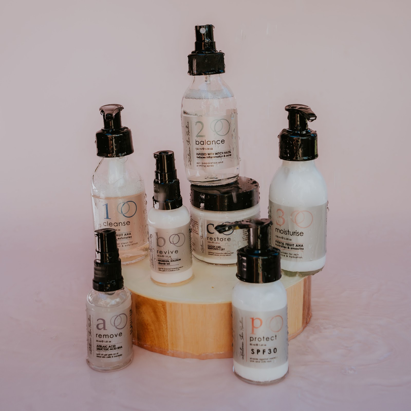 The full In-Between Skin Routine range arranged on a wooden slice